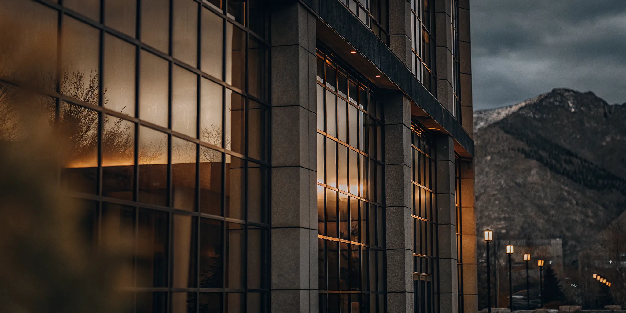 Modern commercial building exterior with glass facade and mountain backdrop at golden hour